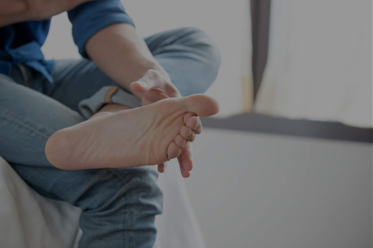 Man touching sweaty feet wondering what he can do to keep his feet dry