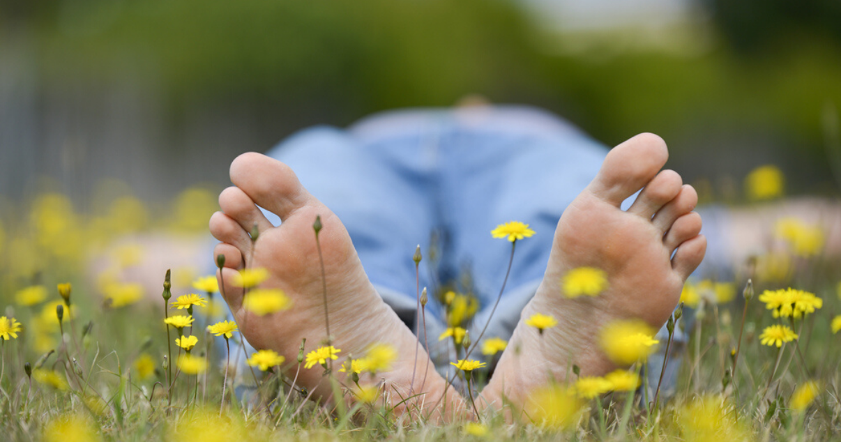 man happily happily lying down on grass after fixing sweaty feet problem