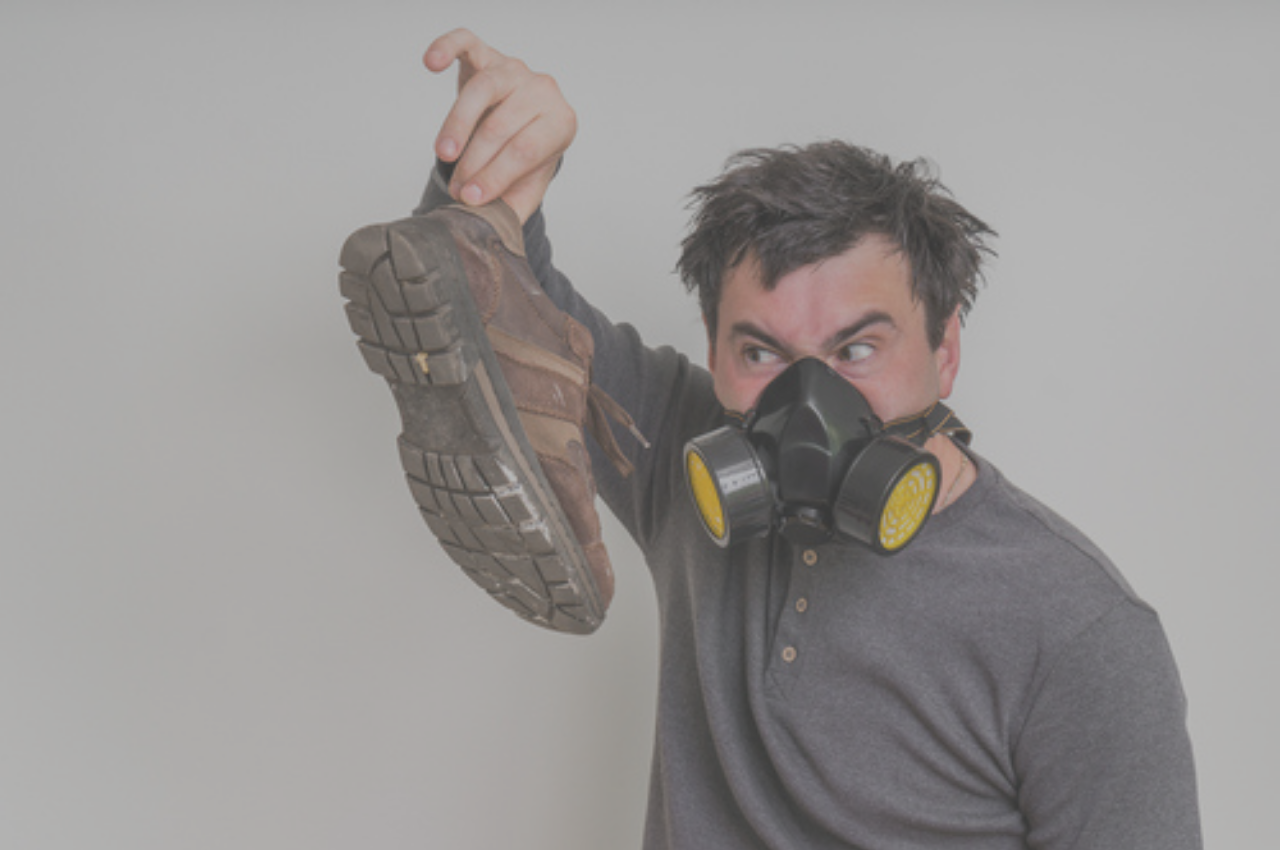 Man holding shoes with strong athlete's foot smell