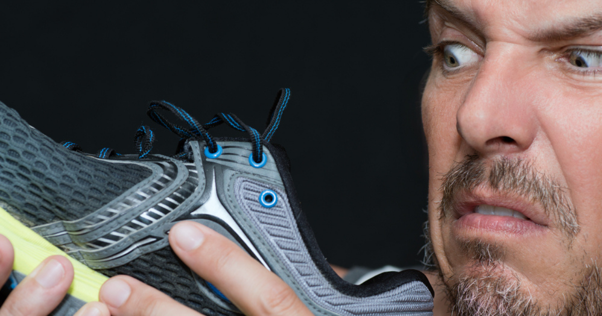 Disgusted man smelling his running shoes wondering if he has an ahletes foot infection