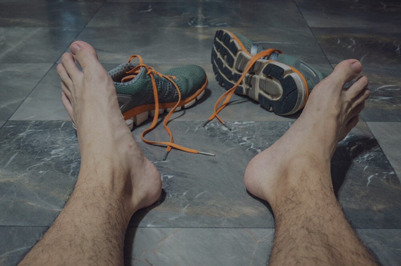 man taking sweaty shoes off wondering which athletes foot treatment is best for him